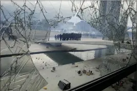  ?? ERALDO PERES — THE ASSOCIATED PRESS FILE ?? Police stand on the other side of a window at Planalto Palace in Brasilia, Brazil, on Jan. 8. It was shattered when supporters of Brazil’s former President Jair Bolsonaro stormed the official workplace of President Luiz Inacio Lula da Silva.