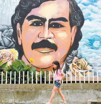  ??  ?? Une fillette marche devant une murale en l’honneur de Pablo Escobar à Medellín. PHOTO AFP