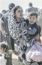  ?? BULENT KILIC/ GETTY IMAGES/FILES ?? A Syrian Kurdish woman and her child cross into Turkey. In Human Flow, Ai Weiwei visits refugees throughout Africa, Asia, the Middle East and Europe.