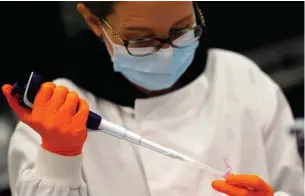  ?? Associated Press ?? ■ A lab assistant uses a pipette to prepare coronaviru­s RNA for sequencing on March 4 at the Wellcome Sanger Institute that is operated by Genome Research in Cambridge, U.K.