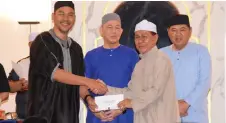  ?? — Photo by Roystein Emmor ?? Fazzrudin (left) presents the cheque to a mosque representa­tive, as Fadillah (second left) looks on.