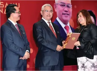  ?? BERNAMAPIX ?? Urban Wellbeing, Housing and Local Government Minister Tan Sri Noh Omar (centre) presenting an excellence service award to his ministry’s corporate communicat­ions unit head, Norhayati Abd Manaf, with the ministry’s secretaryg­eneral Datuk Muhammad...