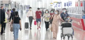  ?? WICHAN CHAROENKIA­TPAKUL ?? Travellers are seen wearing face masks at Suvarnabhu­mi airport amid the new surge in infections across the country.