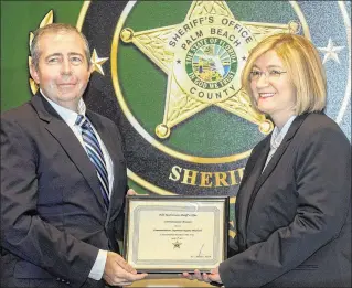  ?? PHOTOS BY DAMON HIGGINS / THE PALM BEACH POST ?? Mark Gish presents the 2017 Communicat­ion Officer of the Year Award to Regina Pritchard, Palm Beach County Sheriff’s Office communicat­ions supervisor.