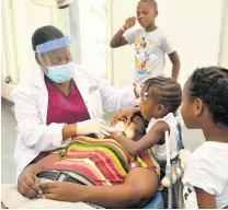 ??  ?? Three-year-old Taniel Lewis assists dental hygienist Danielle Williams, a final-year student at the University of Technology, Jamaica’s School of Dentistry, to open her mother Debbi-Ann Jolly’s mouth. Looking on are Canefa Simpson and Twayne Tucker (second left).
