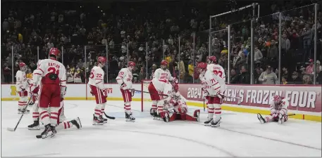  ?? ABBIE PARR — THE ASSOCIATED PRESS ?? Boston University players sit and stand on the ice after an overtime loss to Denver in a semifinal game at the Frozen Four NCAA college hockey tournament Thursday, April 11, 2024, in St. Paul, Minn.