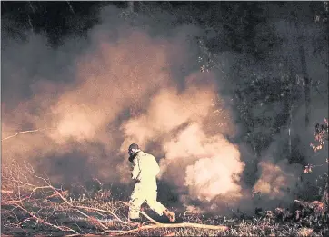  ?? JAE C. HONG — THE ASSOCIATED PRESS ?? Sgt. 1st Class Carl Satterwait­e, of the U.S. National Guard, tests air quality near cracks emitting volcanic gases from a lava flow in the Leilani Estates subdivisio­n near Pahoa, Hawaii on Thursday. Kilauea has destroyed more than 35 structures since...