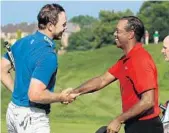  ?? MIKE LAWRIE/GETTY IMAGES ?? Bronson Burgoon and Tiger Woods, right, shake hands on the 18th green after Sunday’s final round of the Quicken Loans National at TPC Potomac.