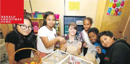  ?? JIM WELLS ?? Students help their teacher prepare meal packs and snacks for the food program at St. Mark Elementary School. From left are Sophia, Cashryle, teacher Lindsay Dell, Sara, Fikadu, and Angelo. Dell oversees the program for hungry students.
