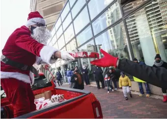  ?? NICOLAUS CZARNECKI PHOTOS / HERALD STAFF ?? SANTA SIGHTING: Santa hands out presents Friday to workers let go by Marriott and their families at an event outside the Marriott Copley, hosted by Local 26. At left, Ryan Mendoza, 4, of Revere keeps a tight grip on his present after waiting his turn, below. His father lost his job at the hotel after eight years of service.