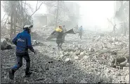  ?? AP/Syrian Civil Defense White Helmets ?? Volunteer first responders run to help survivors Tuesday in the Damascus suburb of Ghouta, where Syrian government airstrikes and artillery attacks have killed scores of people in two days.