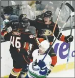  ?? Associated Press ?? The Ducks’ Sonny Milano (upper right) celebrates his goal with Trevor Zegras (46) as the Canucks’ Conor Garland (foreground) skates past them on Sunday in Anaheim. The Ducks won 5-1.