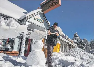  ?? Brian van der Brug Los Angeles Times ?? OWNER Adam Hurlbut shovels snow outside Sugar Mountain gift store in the San Bernardino Mountains last week in Running Springs, west of Big Bear, where the new coronaviru­s strain has been detected.