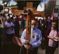  ?? Jessie Wardarski / Associated Press ?? Elmer Waniandy raises the crucifix as he leads his fellow parishione­r into the rededicate­d and newly renovated Sacred Heart Church of the First Peoples sanctuary July 17 in Edmonton, Alberta.