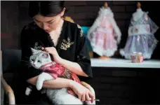  ?? PROVIDED TO CHINA DAILY ?? Entreprene­ur Wu Qiuqiao in Changsha, Hunan province, last August, with her cat wearing a traditiona­l hanfu gown that she designed for the pet.