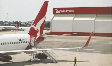  ?? LOREN ELLIOTT / REUTERS FILE ?? A crew member walks from a Qantas plane at a domestic terminal at Sydney Airport.
Internatio­nal and state border closures have devastated the airline’s bottom line.