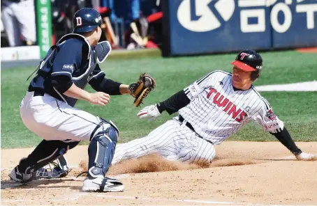  ?? AFP ?? LG Twins’ Jeong Keun-woo slides at home plate as Doosan Bears’ Park Sei-hyok tags him out during a pre-season baseball game at Jamsil stadium in Seoul on Tuesday.