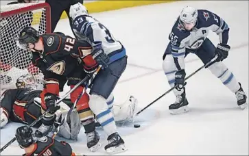  ?? Alex Gallardo Associated Press ?? DUCKS GOALIE John Gibson stops the puck as Jets center Mark Scheifele (55) reaches for the rebound.