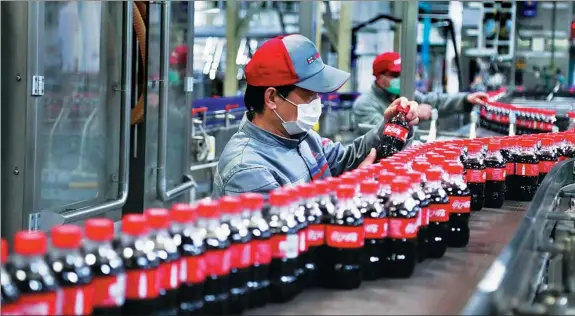  ?? YANG YANJUN / CHINA NEWS SERVICE ?? Top: Employees work on the production line of a Coca-Cola venture in Shanghai.