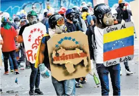  ?? CARLOS GARCIA RAWLNIS/REUTERS ?? Encapuchad­os respondían agresiones con piedras y cocteles molotov.