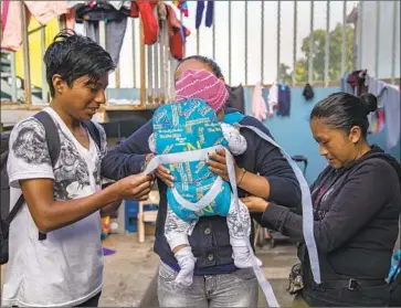  ?? Gina Ferazzi Los Angeles Times ?? HUNDREDS OF migrants have been returned to Mexico under a new U. S. policy to have some asylum seekers wait there while their cases are pending. Above, a family prepares to present themselves at the border in June.