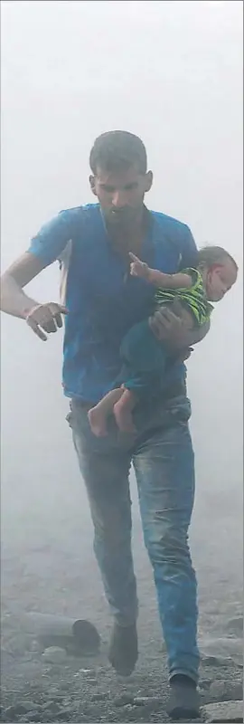  ?? AMER ALMOHIBANY / AFP ?? Un home i el seu nadó fugint d’un bombardeig als afores de Damasc