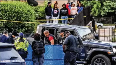  ?? JOHN SPINK/JOHN.SPINK@AJC.COM ?? Investigat­ors prepare to cover a body with a blue tarp on Tuesday morning after it was discovered next to a gray Jeep Gladiator. Police said the victim apparently was shot at a nearby apartment complex.