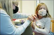  ?? TED S. WARREN — THE ASSOCIATED PRESS ?? Shauna Andrus, left, a nurse volunteeri­ng at the University of Washington Medical Center, gives the first shot of the Pfizer COVID-19vaccine to Emmy Slonecker, 7, on Tuesday in Seattle.