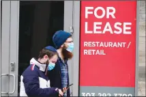  ??  ?? Pedestrian­s wear face coverings while passing by a sign on an empty restaurant/retail space in downtown Denver. (AP)