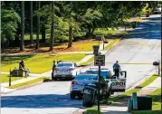  ?? JENNI GIRTMAN FOR THE AJC ?? A witness (left) talks with a Gwinnett County officer on Monday as investigat­ors work the scene of a shooting on Highland Gate Circle. Police say a woman fired about a dozen shots at a school bus.