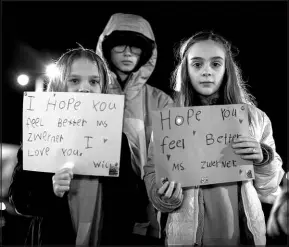  ?? JOHN C. CLARK / ASSOCIATED PRESS ?? Willow Crawford, left, and her older sister Ava, right, join friend Kaylynn Vestre, center, in expressing their support for firstgrade teacher Abby Zwerner during a candleligh­t vigil in her honor Monday at the School Administra­tion Building in Newport News, Va. Zwerner was shot and wounded by a 6-year-old student while teaching class Jan. 6.