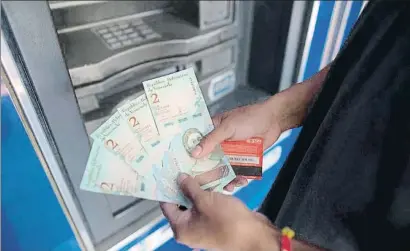  ?? ARIANA CUBILLOS / AP ?? Un venezolano muestra los nuevos bolívares recién sacados de un cajero automático