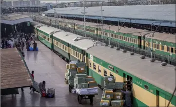  ?? — Bloomberg photos by Asim Hafee ?? Employees on a platform load boxes into a luggage coach of a Green Line Express train operated by Pakistan Railways between Islamabad and Karachi in Rawalpindi.