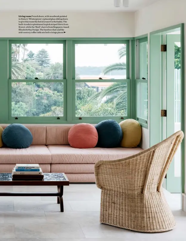  ??  ?? Living room French doors, with woodwork painted in Dulux’s ‘Wintergree­n’, replaced glass sliding doors to give this room the feel of a resort in Barbados. The built-in sofa is upholstere­d in pink striped fabric from Kravet, while the ‘Shell’ chair is from Singapore-based Elizabeth Hay Design. The bamboo chair and the mid-century coffee table are both vintage pieces