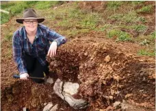  ??  ?? Geologist Dr Julie Boyce with a volcanic ‘bomb’ embedded into the side of Red Rock, a volcanic complex north of Colac.