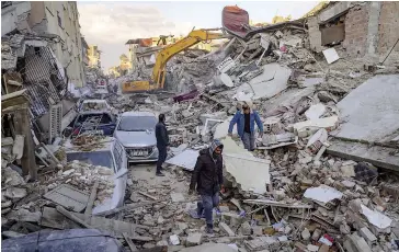  ?? PHOTO AFP ?? Des gens traversent les décombres d’un bâtiment effondré à Antakiya, dans le sud de la Turquie, dans l’espoir de retrouver des survivants.