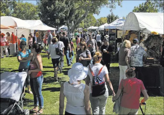  ?? Gabriella Benavidez Las Vegas Review-Journal @latina_ish ?? Art in the Park festival patrons mill around the Boulder City park grounds Saturday. Coming on the heels of the Strip mass shooting days earlier, the event attracted a sizable crowd.