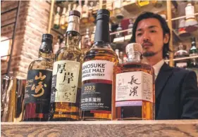  ?? PHOTO: RICHARD A. ?? Whisky library manager Junpei Kusunoki displaying various Japanese whiskies at a bar in Tokyo.
BROOKS/AFP