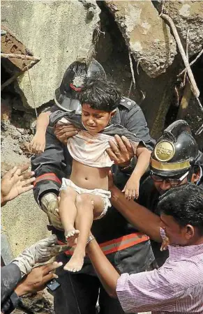  ??  ?? In safe hands: Indian firemen rescuing a girl from the debris of the collapsed building in Mumbai, India. — AP