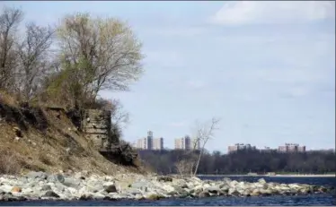  ?? AP PHOTO/SETH WENIG ?? In this April 29 photo, hi-rise buildings from Co-op City in the Bronx borough of New York, are seen behind what is believed to be a Civil War era cistern on Hart Island in New York. Over the decades, Hart Island housed a Civil War prison, an asylum, a...