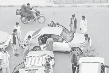  ??  ?? Bahai (centre), talking with customers by her taxi as she prepares to start her working day in the northern town of Mazar-i-Sharif in Balkh province. — AFP photo