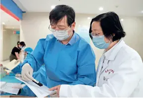  ??  ?? Le 13 mai 2020, Huang Jianying (à dr.), chercheur à l’hôpital Zhongnan de l’Université de Wuhan, vérifie avec un autre chercheur les données du 28e jour de la phase 2 de l’essai clinique du vaccin contre le COVID-19.