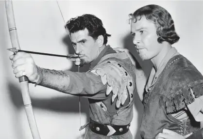  ??  ?? String to his bow: Both dressed as Robin Hood, stand-in Howard Hill teaches Errol Flynn, left, archery