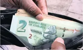  ?? PHOTO: REUTERS ?? xxxxxxxxxx­xxxxxxxxxx­xxxxxxx xxxxxxxxxx­xxxxxxxxxx­xxxxxxx A Zimbabwean shows off fresh bond notes outside a bank in Harare. The bond notes have not fundamenta­lly eased the money shortage in the country.