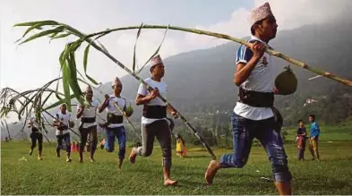  ??  ?? PESERTA festival Shikali
berlari membawa batang tebu di Lalitpur, Nepal. - Reuters