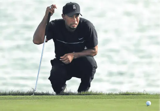  ??  ?? Tiger Woods is a study in concentrat­ion as he lines up this putt on the 17th green.