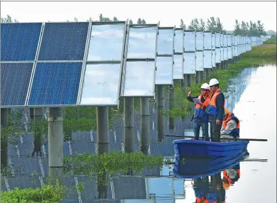  ?? SONG WEIXING / FOR CHINA DAILY ?? Workers check solar power generation facilities in Tianchang, East China’s Anhui province.