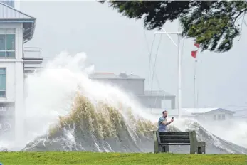  ?? FOTO: GERALD HERBERT/DPA ?? Ein Mann macht ein Selfie, während sich hinter ihm eine Welle auftürmt, als der Hurrikan „Ida“im Us-bundesstaa­t Louisiana auf Land trifft. Das Nationale Hurrikanze­ntrum stufte „Ida“als „extrem gefährlich“ein.