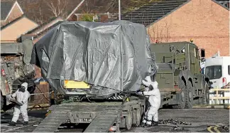  ?? PHOTOS: AP ?? Investigat­ors in gas masks move a wrapped ambulance from the South Western Ambulance Service station in Harnham, near Salisbury, England, as police and members of the armed forces probe the suspected nerve agent attack on Russian spy double agent...