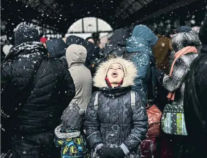  ?? BErcel ernecANa / eJ ?? Una nena boqueja per agafar neu a la ciutat ucraïnesa de Lviv en espera del tren cap a Polònia